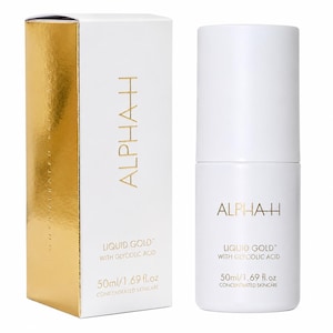 Puede incluir: Una caja rectangular blanca y dorada junto a un frasco cilíndrico blanco de Alpha-H Liquid Gold with Glycolic Acid. Ambos artículos presentan texto dorado e indican un volumen de 50ml/1.69 fl.oz. El envase está etiquetado como cuidado de la piel concentrado.