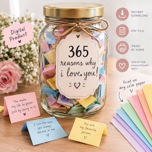 May include: A clear glass jar with a gold lid, filled with colorful folded paper notes. A beige tag tied with twine reads 365 reasons why i love you! with heart icons. Three small folded notes with printed text sit in front of the jar.