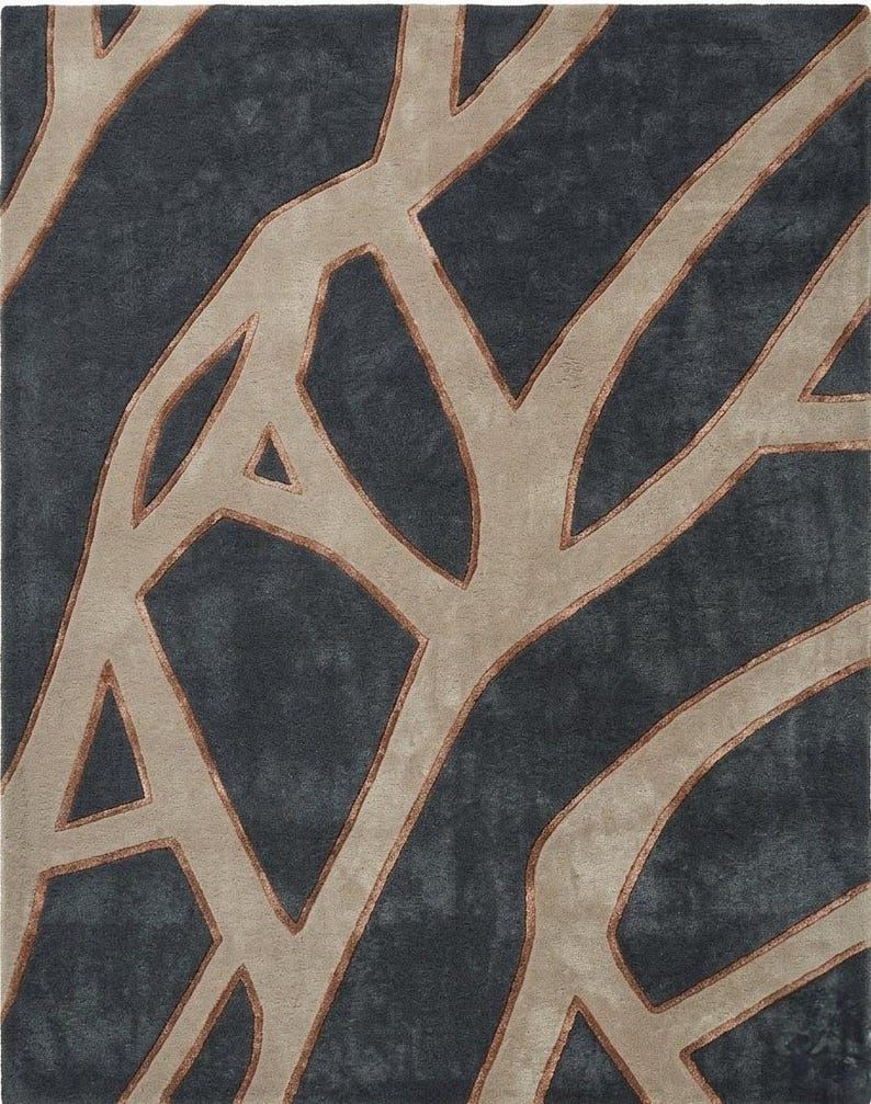 May include: A rectangular area rug with a tree branch design. The rug features a dark gray background with beige and brown branch-like patterns. The design is abstract and modern, suitable for a living room or bedroom.