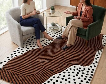 Alfombra abstracta hecha a mano con mechones, lunares blancos y negros, y rayas onduladas marrones.