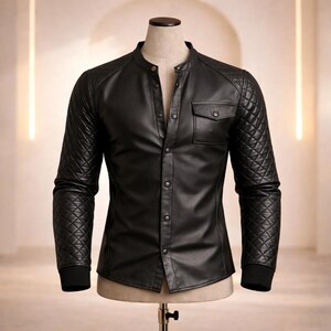 May include: Black leather shirt with a quilted design on the sleeves and shoulders. The shirt has a mandarin collar, a single chest pocket, and a button-up front. The cuffs are black and ribbed.