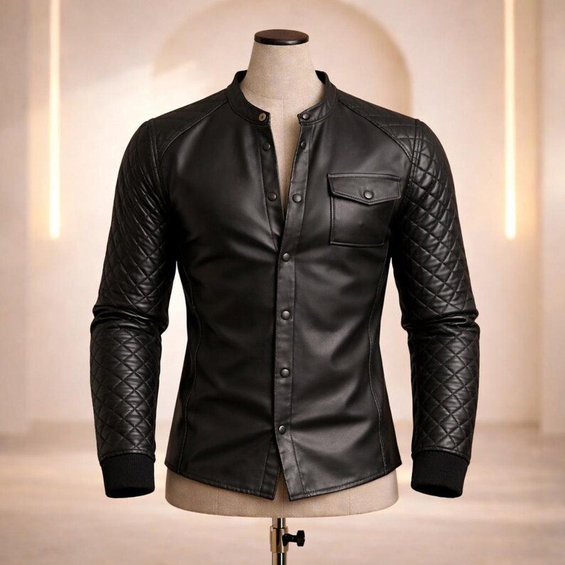 May include: Black leather shirt with a quilted design on the sleeves and shoulders. The shirt has a mandarin collar, a single chest pocket, and a button-up front. The cuffs are black and ribbed.