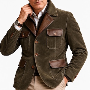Puede incluir: Chaqueta de ante verde oliva oscuro con detalles de cuero marrón en el cuello y los bolsillos. La chaqueta tiene cuatro bolsillos delanteros, cierre de botones y un reloj marrón. Se lleva sobre una camisa blanca y un suéter marrón.