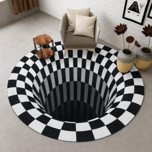 Puede incluir: Una alfombra redonda a cuadros blancos y negros que crea una ilusión óptica 3D de un agujero profundo. La alfombra está sobre un suelo gris. Una silla y una mesa auxiliar son visibles en el fondo.