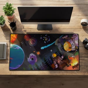 Pode incluir: Um tapete de rato retangular com uma ilustração colorida com tema espacial. O design inclui planetas, uma nave espacial, um astronauta e uma fogueira contra um fundo escuro e estrelado. O tapete está colocado numa secretária de madeira com um monitor de computador e acessórios.