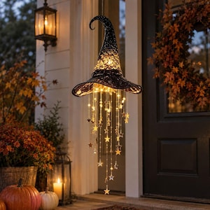 Può includere: Una decorazione a forma di cappello da strega nero a punta con un design testurizzato a trama aperta. Il cappello è illuminato dall'interno e decorato con molteplici fili pendenti di ornamenti trasparenti a forma di stella che emettono una luce calda.