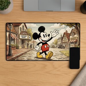 Può includere: Tappetino per mouse rettangolare con un'illustrazione di cartoni animati di Mickey Mouse che cammina su una strada acciottolata. La scena include un cinema con l'insegna "Cartoon Short" e una panetteria. Il tappetino ha un bordo nero.