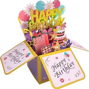 May include: A pop-up birthday card in a box design. The card features a gold glitter "Happy Birthday" message, balloons, gifts, a cake, and stars. The box has "Happy Birthday" text on the front and sides.