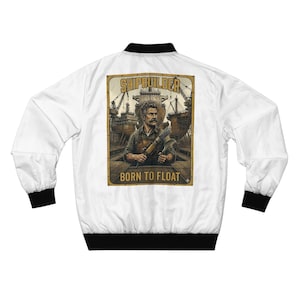 May include: White bomber jacket with black trim and cuffs. The back features a vintage-style illustration of a shipbuilder holding tools, with the text "SHIPBUILDER" and "BORN TO FLOAT" in a gold-colored font.