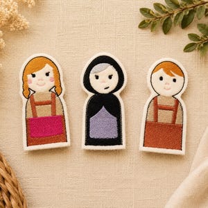 May include: Three felt finger puppets. The puppets are in the shape of people, with embroidered details. One has orange hair and a pink apron, the second has gray hair and a black cloak, and the third has orange hair and a brown apron.