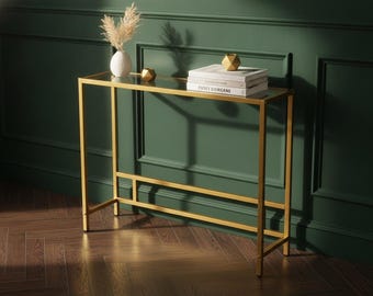 Una moderna mesa consola dorada con tablero de cristal templado y estructura metálica, perfecta para recibidores, pasillos, salas de estar y oficinas.