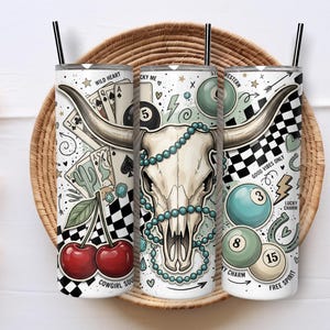 May include: Three cylindrical tumblers with black straws featuring a graphic print of a longhorn skull, playing cards, cherries, billiard balls, and checkered patterns. Text includes Wild Heart, Lucky Me, Western, Good Vibes Only, and Free Spirit.