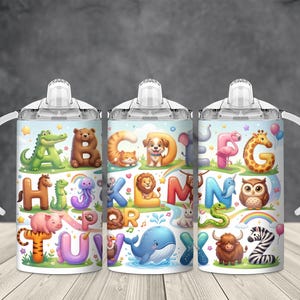 May include: Three white sippy cups with handles, each featuring a colorful alphabet design with animals. The letters are paired with illustrations of an alligator, bear, cat, dog, flamingo, giraffe, and more. The cups have a light blue background.