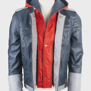 May include: A multi-layered jacket featuring a dark blue outer shell with light gray cuffs and shoulder accents, a bright red inner panel with gold-tone snap buttons, and a hood with a vibrant orange lining, displayed on a mannequin torso.