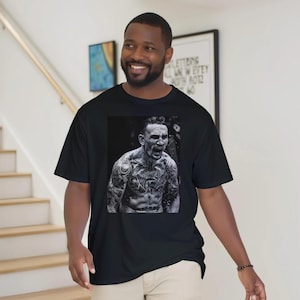 May include: Black t-shirt featuring a black and white image of a man with tattoos, yelling. The t-shirt is made of a soft material and is a crew neck style. The image is centered on the front of the shirt.