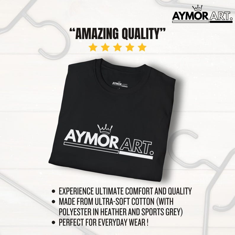 May include: A black short-sleeved t-shirt featuring the white text AYMOR ART. with a crown icon above the letters. The shirt is displayed flat with a round neckline and a brand label on the inside collar. The design includes a horizontal line.