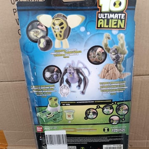 May include: Rear of a Ben 10 Ultimate Alien action figure package. The packaging displays images of several alien characters, such as Terraspin, Ultimate Humungousaur, and Ultimate Spidermonkey. The colour scheme is predominantly blue and green.