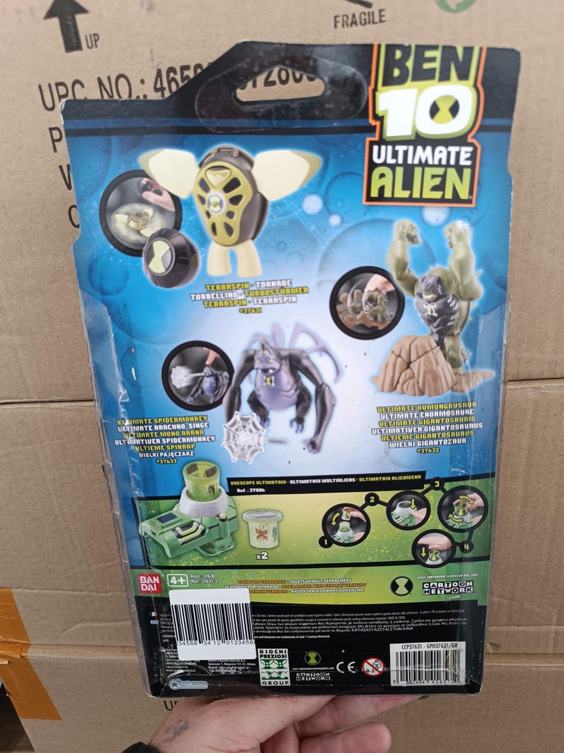 May include: Rear of a Ben 10 Ultimate Alien action figure package. The packaging displays images of several alien characters, such as Terraspin, Ultimate Humungousaur, and Ultimate Spidermonkey. The colour scheme is predominantly blue and green.