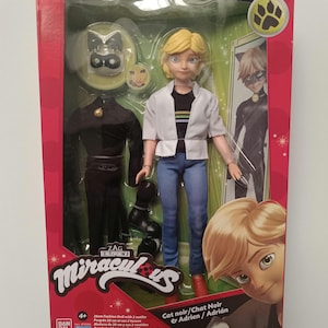May include: A boxed Miraculous fashion doll set featuring a doll with blonde hair, blue jeans, and a white jacket. The set includes a black outfit and accessories. The packaging is red with character illustrations and the text "Miraculous".
