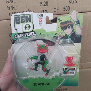 May include: A Ben 10 Omniverse action figure of Juryrigg in a clear plastic package. The figure is red, green, and black. The packaging features the Ben 10 logo, a cartoon image of Ben, and the text "Omnitrix Challenge".