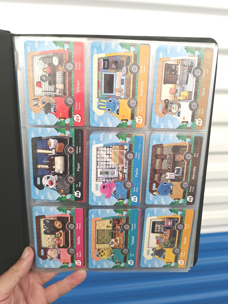 May include: A black card binder holding nine colorful trading cards. Each card features a unique character and interior scene, with names like Vivian, Hopkins, and June. The cards are in a protective sleeve.