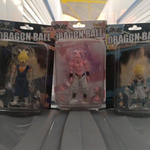 Puede incluir: Tres figuras de acci&oacute;n de Dragon Ball en embalajes de pl&aacute;stico transparente. Las figuras son de varios personajes con dise&ntilde;os detallados y colores vibrantes. El embalaje incluye el texto "Dragon Ball" y los nombres de los personajes.