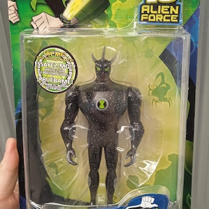 Pode incluir: Uma figura de ação Alien X de Ben 10 Alien Force, embalada em blister de plástico transparente. A figura é preta com salpicos brancos e detalhes verdes. A embalagem inclui o logotipo Ben 10 e texto em vários idiomas.