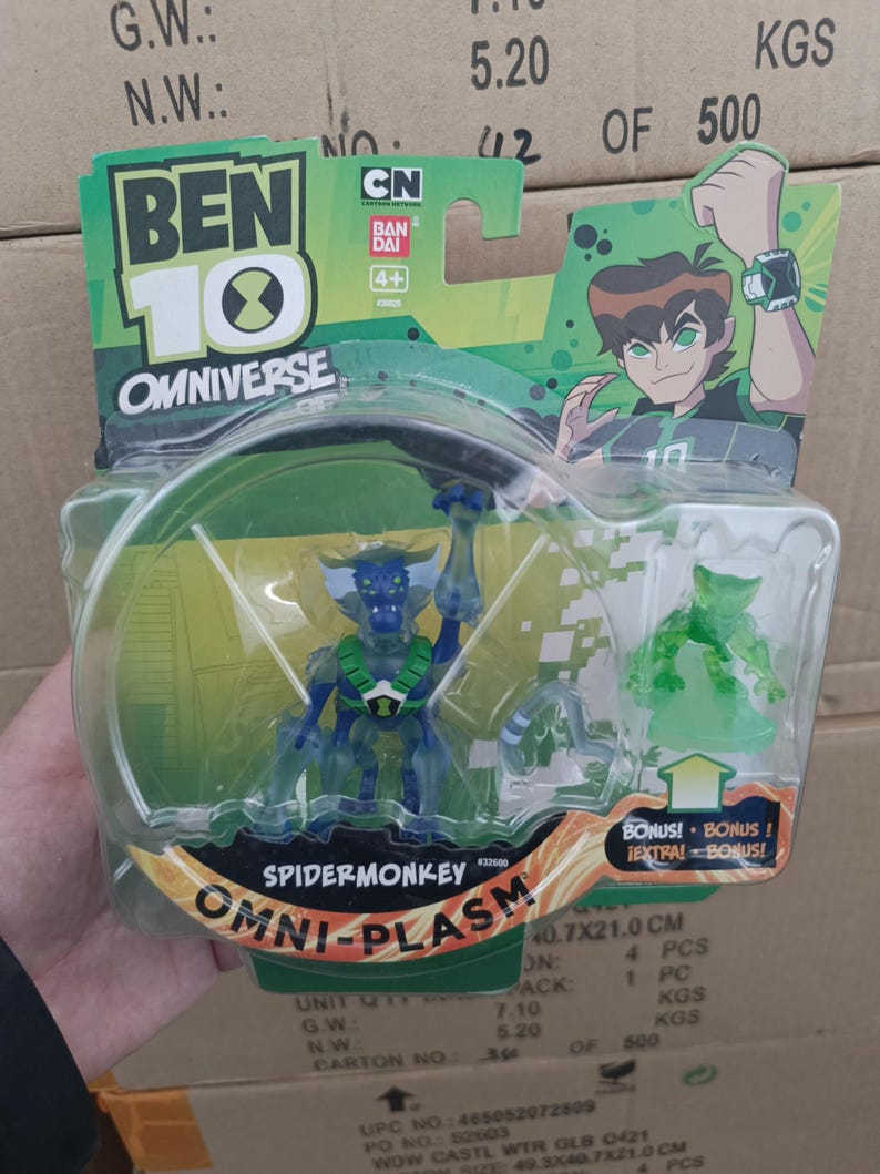 May include: A Ben 10 Omniverse SpiderMonkey Omni-Plasm action figure in a clear plastic package. The figure is blue and green, with a detailed design. The packaging includes the Ben 10 logo, CN, and Bandai branding. The package dimensions are 40.7 x 21.0 cm.