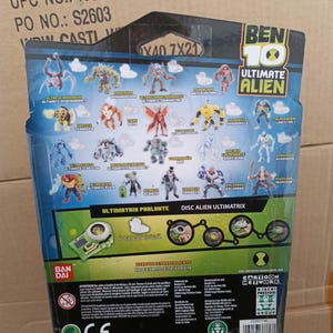 Puede incluir: Parte trasera de un paquete de juguetes Ben 10 Ultimate Alien. El paquete presenta varios personajes alien&iacute;genas y el texto "ULTIMATE ALIEN". El paquete tambi&eacute;n incluye el texto "ULTIMATRIX PARLANTE" y "DISC ALIEN ULTIMATRIX". Dimensiones: 421 cm x 21,0 cm.