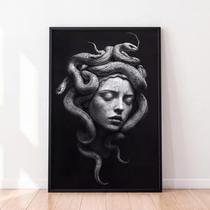 Op de afbeelding: Een zwart-wit ingelijste muurkunstprint met een gedetailleerde illustratie van een gezicht met gesloten ogen, omringd door meerdere slangen die als haar in elkaar verstrengeld zijn. Het kunstwerk is weergegeven in hoog contrast met diepe schaduwen.