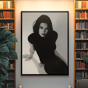 May include: Black and white framed print of a person in a black outfit. The print is displayed on a white wall, flanked by two tall bookshelves filled with books. A bench and chair are positioned below the print.
