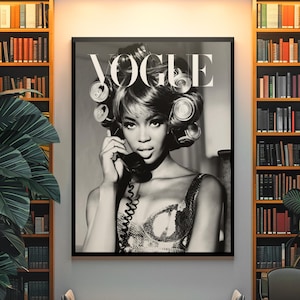 Może przedstawiać: Czarno-biały wydruk okładki magazynu Vogue, w ramie. Przedstawia kobietę z wałkami do włos&oacute;w, trzymającą telefon. Wydruk wisi nad ławką w pokoju z regałami z książkami.