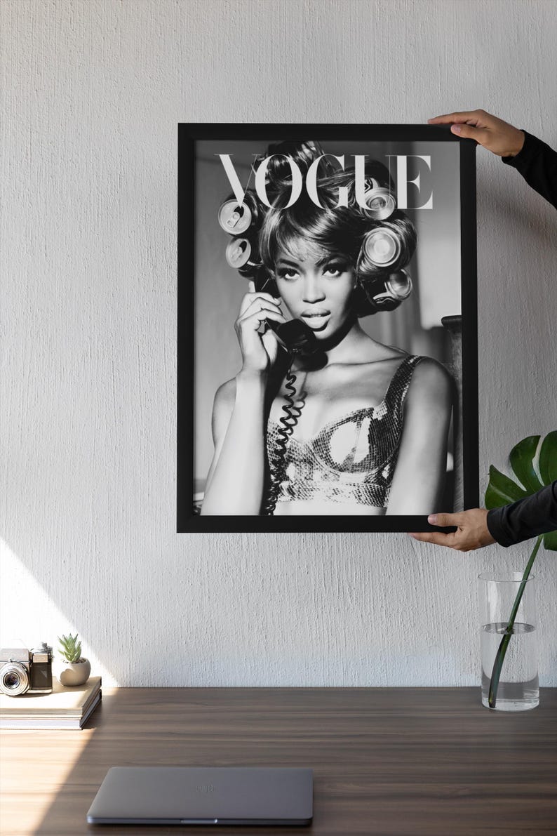 Może przedstawiać: Czarno-biały oprawiony wydruk przedstawiający kobietę z wałkami do włos&oacute;w, trzymającą telefon. Widoczne logo Vogue. Wydruk trzymany przez osobę. Estetyka vintage.