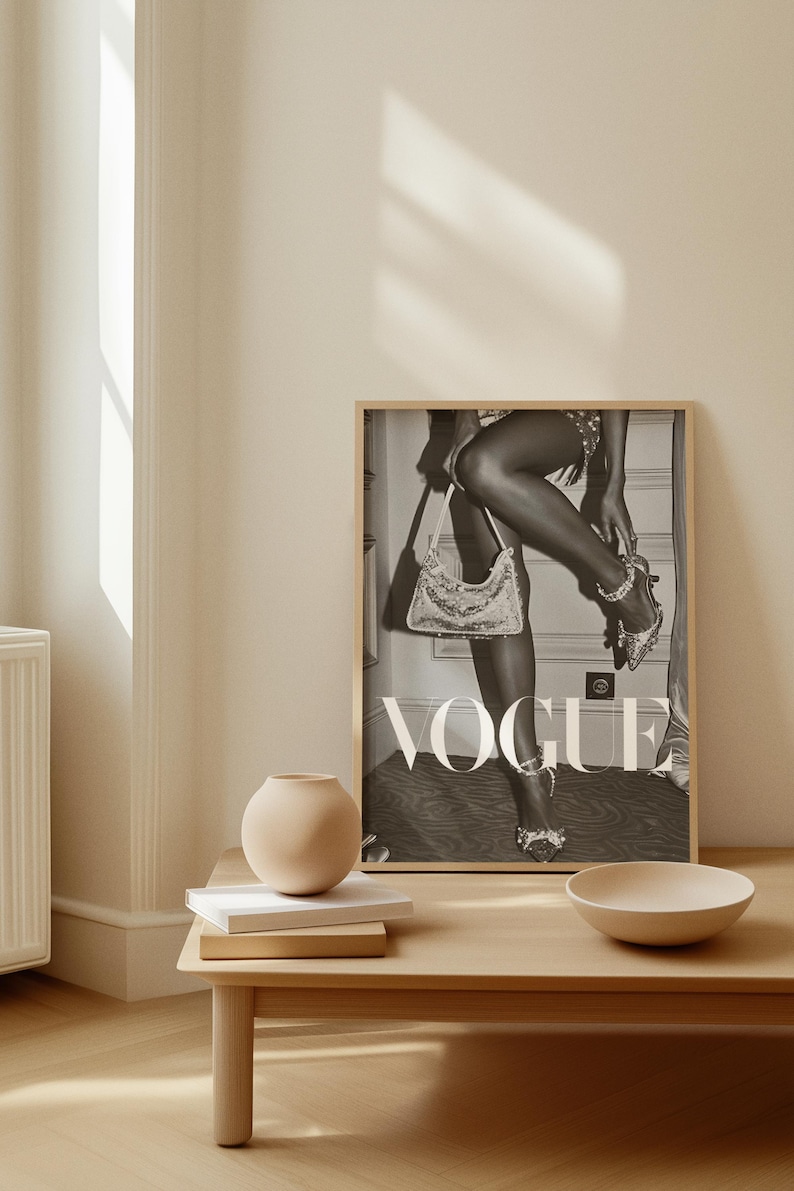 May include: A framed black and white Vogue magazine cover print. The image features a person wearing embellished high heels and holding a sequined handbag. The word "VOGUE" is prominently displayed in large white letters.