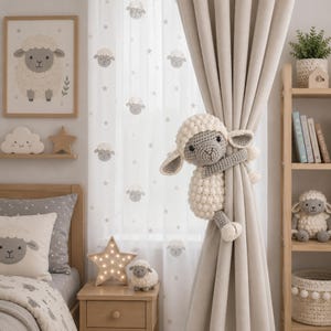 May include: A crochet sheep curtain tieback featuring a cream-coloured textured body and a grey face with dark eyes. The sheep is designed to wrap its arms around a beige curtain panel, serving as a functional and decorative accessory for window treatments.