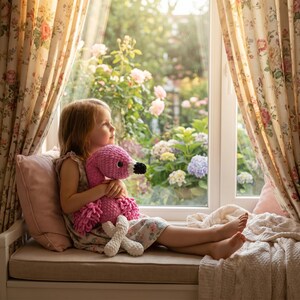 Little girl holding crochet flamingo toy by sunny window, thoughtful gift for toddlers