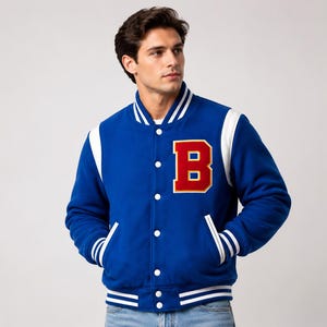 May include: A royal blue varsity jacket with white accents on the shoulders, collar, and cuffs. The jacket features a large red letter "B" on the chest, a button-up front, and two front pockets. The jacket is a classic style.