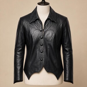 May include: A black leather jacket with a notched collar and five buttons. The jacket has a fitted silhouette with curved seams and a pointed hemline. The sleeves are long and the jacket is displayed on a mannequin.