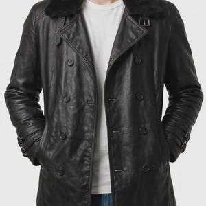 May include: Black leather jacket with a faux fur collar. The double-breasted coat features multiple buttons, a notched lapel, and buckle details on the sleeves. The jacket has two front pockets and is worn over a white t-shirt.