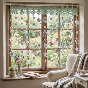 May include: A window with a crocheted valance and floral curtain. The curtain features strings of crocheted flowers in pastel colors, including pink, blue, and purple. A cozy armchair and a small table with a teacup are in the room.