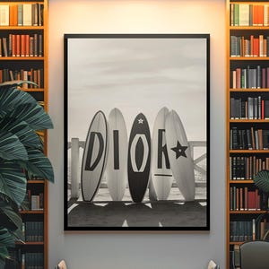 May include: Black and white framed print featuring five surfboards leaning against a wooden fence. The surfboards display the word "DIOR" in bold letters and a star. The image is in a sepia tone, evoking a vintage aesthetic.