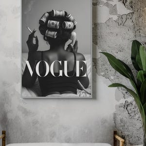 Puede incluir: Impresi&oacute;n en blanco y negro enmarcada que presenta a una mujer con billetes de d&oacute;lar en sus rulos, sosteniendo un cigarrillo y un tel&eacute;fono antiguo. La palabra "VOGUE" se muestra de forma destacada en texto blanco.
