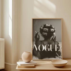 Puede incluir: Impresi&oacute;n en blanco y negro con la palabra "VOGUE" y una mujer con rulos de billetes, fumando y sosteniendo un auricular telef&oacute;nico. Un peque&ntilde;o jarr&oacute;n, libros y un cuenco est&aacute;n sobre una mesa de madera.