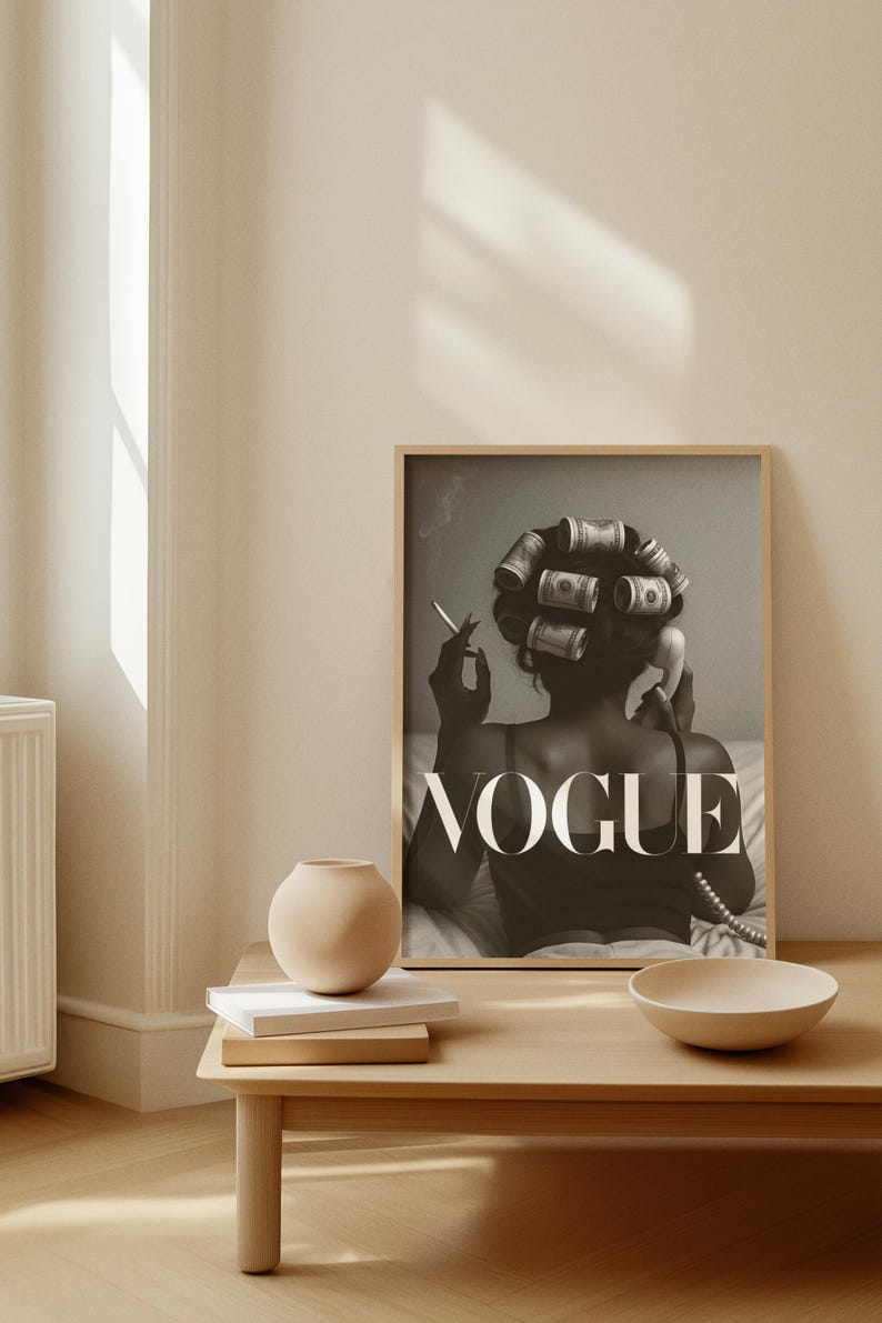 Puede incluir: Impresi&oacute;n en blanco y negro con la palabra "VOGUE" y una mujer con rulos de billetes, fumando y sosteniendo un auricular telef&oacute;nico. Un peque&ntilde;o jarr&oacute;n, libros y un cuenco est&aacute;n sobre una mesa de madera.