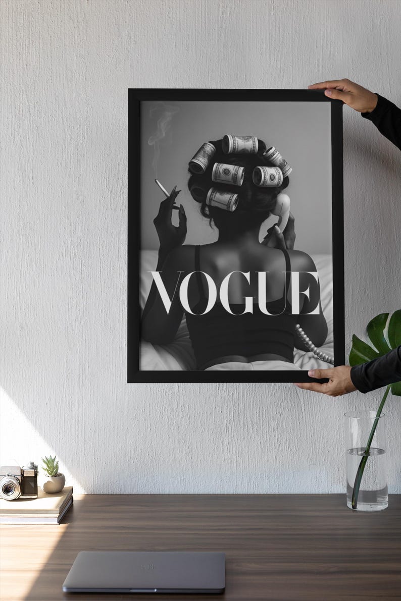 Puede incluir: Impresi&oacute;n en blanco y negro enmarcada que muestra a una mujer con rulos de dinero, fumando un cigarrillo y usando un tel&eacute;fono antiguo. La palabra "VOGUE" se muestra. La impresi&oacute;n es sostenida por una persona.