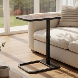 May include: A black adjustable side table with a rectangular, wood-look top. The table has a square base and is positioned next to a beige sofa. The table's height is adjustable.