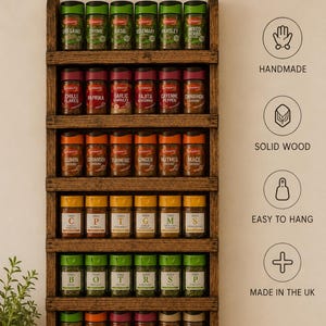 Könnte beinhalten: Ein dunkelbraunes Gewürzregal aus Holz mit sechs horizontalen Ablagen, die jeweils sechs Gewürzgläser enthalten. Oben steht der Text RUSTIC SPICE RACK und PERFECT FOR ORGANISING YOUR SPICES, ergänzt durch Symbole für HANDMADE, SOLID WOOD, EASY TO HANG und MADE IN THE UK.