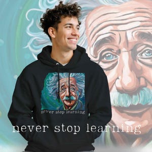Puede incluir: Sudadera con capucha negra con un retrato colorido de Albert Einstein con acentos azules y verdes. El texto "never stop learning" está impreso debajo de la imagen. La sudadera con capucha la lleva una persona.