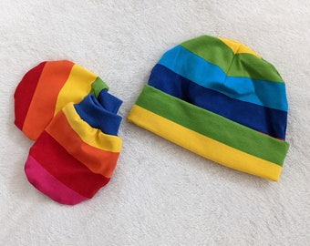 May include: A set of rainbow striped baby mittens and a matching hat. The mittens are folded together and the hat is lying flat.