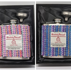 Op de afbeelding: Twee zilveren hipflasks met een trechter in een zwarte doos. De flasks zijn bedekt met een kleurrijke tweed stof met de tekst "HAND WOVEN CLOTH Harris Tweed" en "HARRIS TWEED OUTER HEBRIDES OF SCOTLAND 100% PURE NEW WOOL".